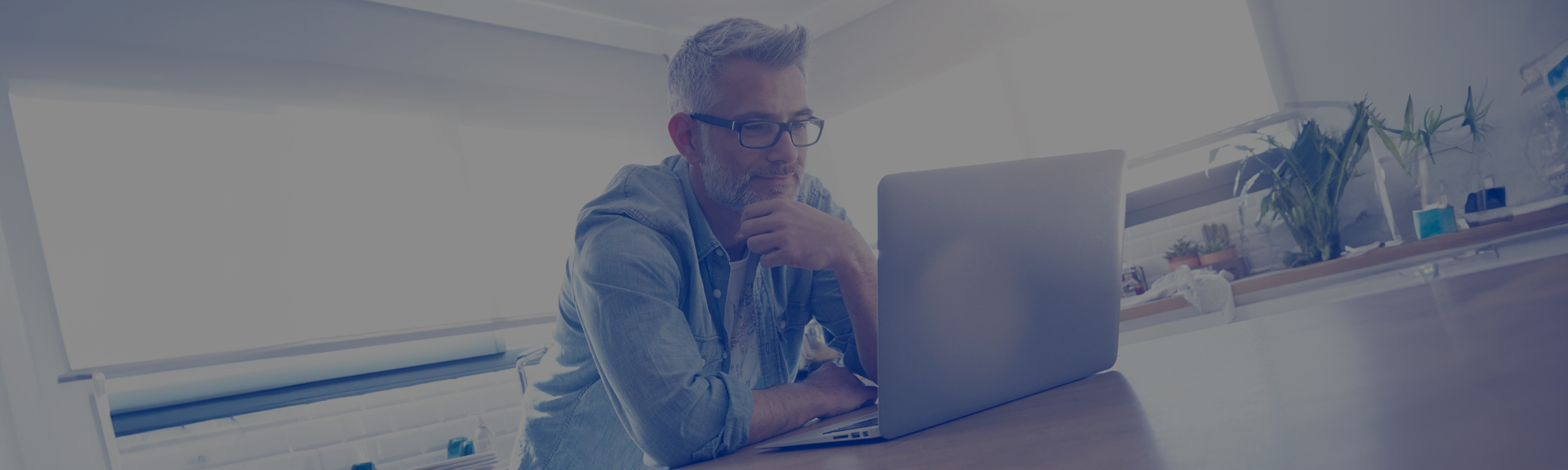 Man looking on computer at home in modern kitchen